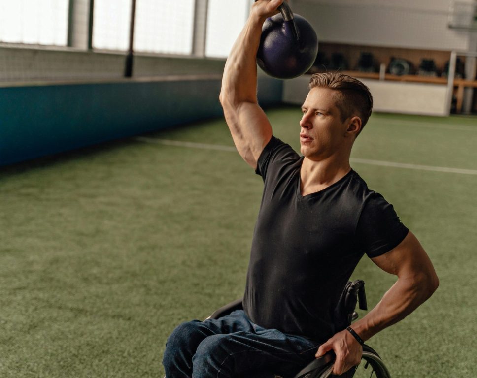 A Man Lifting a Kettlebell while Sitting on His Wheelchair